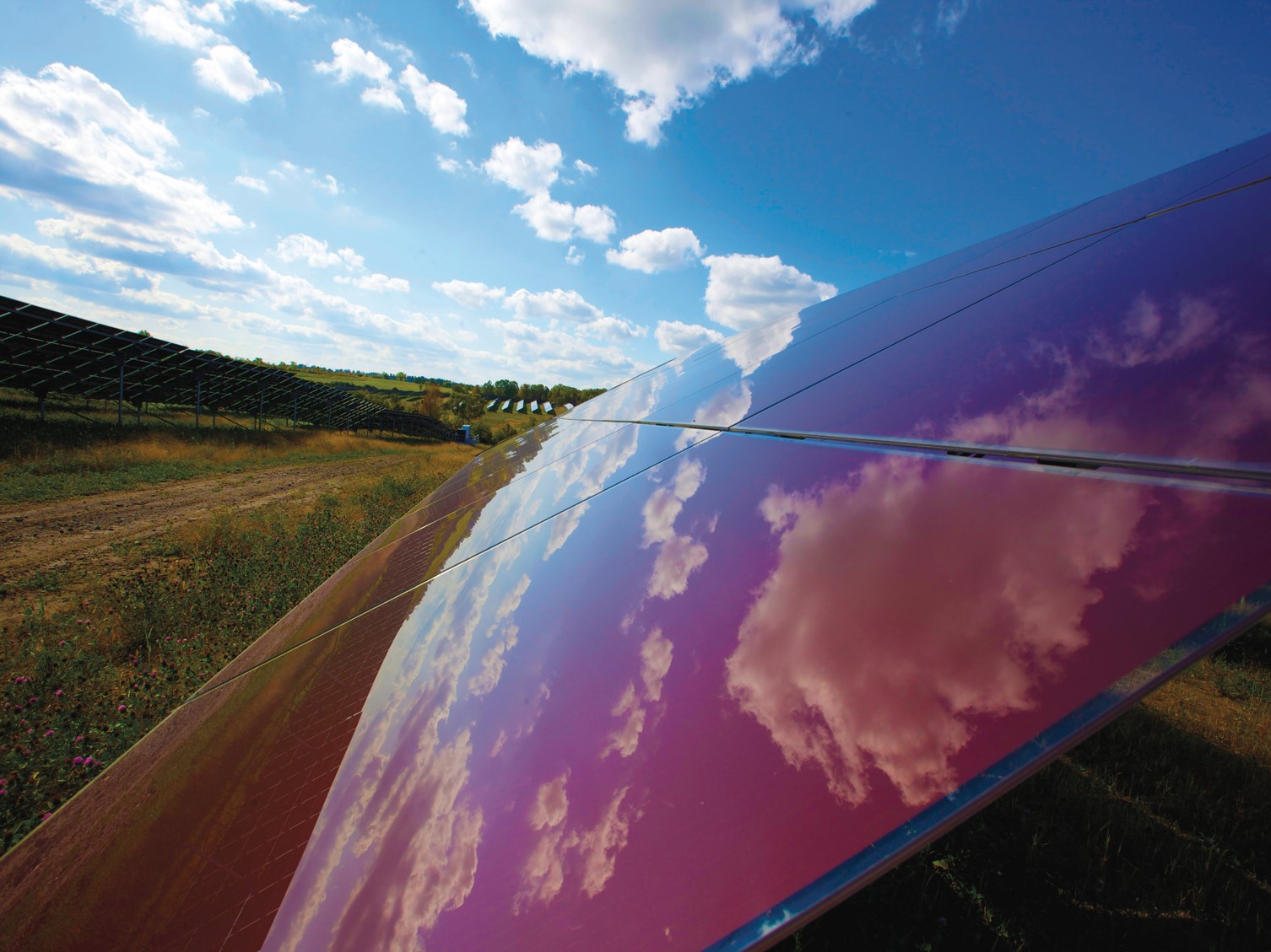More on solar solar panels in a field showing the reflection of clouds in the sky